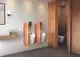 Urinal mit integrierter Betätigungsplatte in Chrom von Ideal Standard. Die Wand ist hell, umgeben von Holzverkleidung. Badezimmerausstattung mit schlichtem Design.